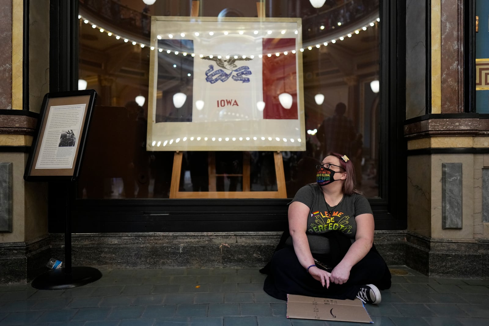 A protesters sits in the rotunda at the Iowa state Capitol to denounce a bill that would strip the state civil rights code of protections based on gender identity, Thursday, Feb. 27, 2025, in Des Moines, Iowa. (AP Photo/Charlie Neibergall)