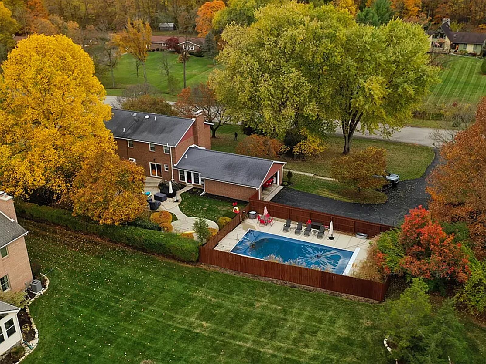 The rear of the home features a saltwater pool with wood privacy fence and a series of brick patios connected by walkways. There is also a shed and firepit.