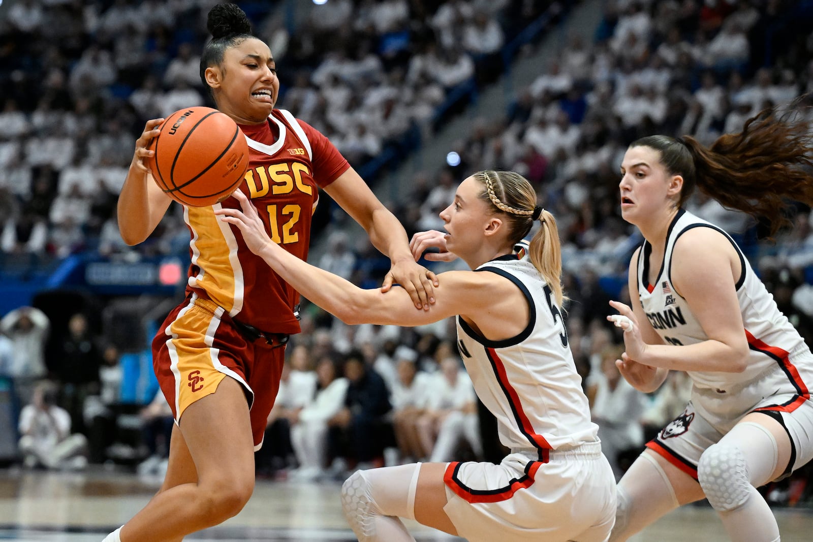 Southern California guard JuJu Watkins, left, drives to the basket as UConn guards Paige Bueckers, center, and Morgan Cheli, right, defend in the second half of an NCAA college basketball game, Saturday, Dec. 21, 2024, in Hartford, Conn. (AP Photo/Jessica Hill)