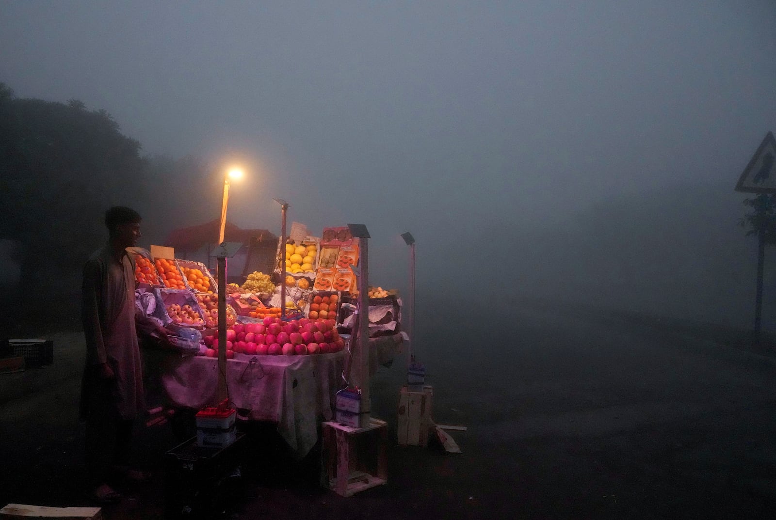 A fruit seller arranges his stall in early morning as smog envelopes the area of Lahore, Pakistan, Thursday, Nov. 14, 2024. (AP Photo/K.M. Chaudary)