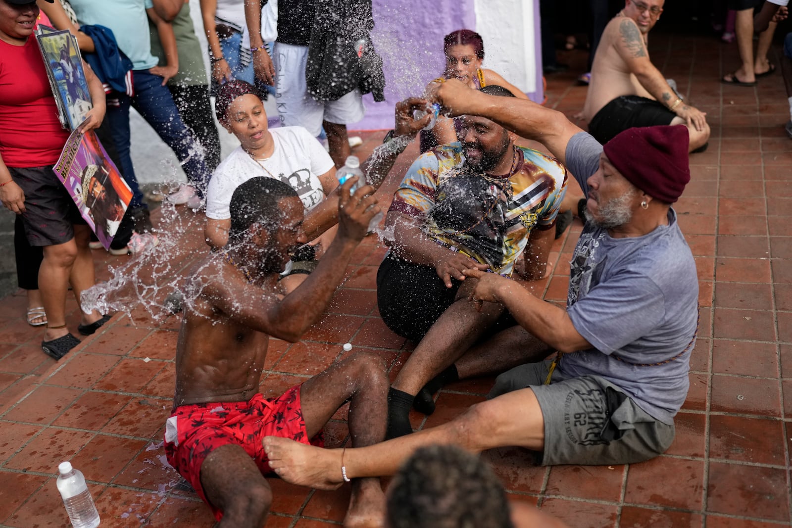 Pilgrims joke around with water after crawling to San Felipe Church to honor the Black Christ in Portobelo, Panama, Monday, Oct. 21, 2024, during a festival celebrating the iconic statue that was found on the shore in 1658. (AP Photo/Matias Delacroix)