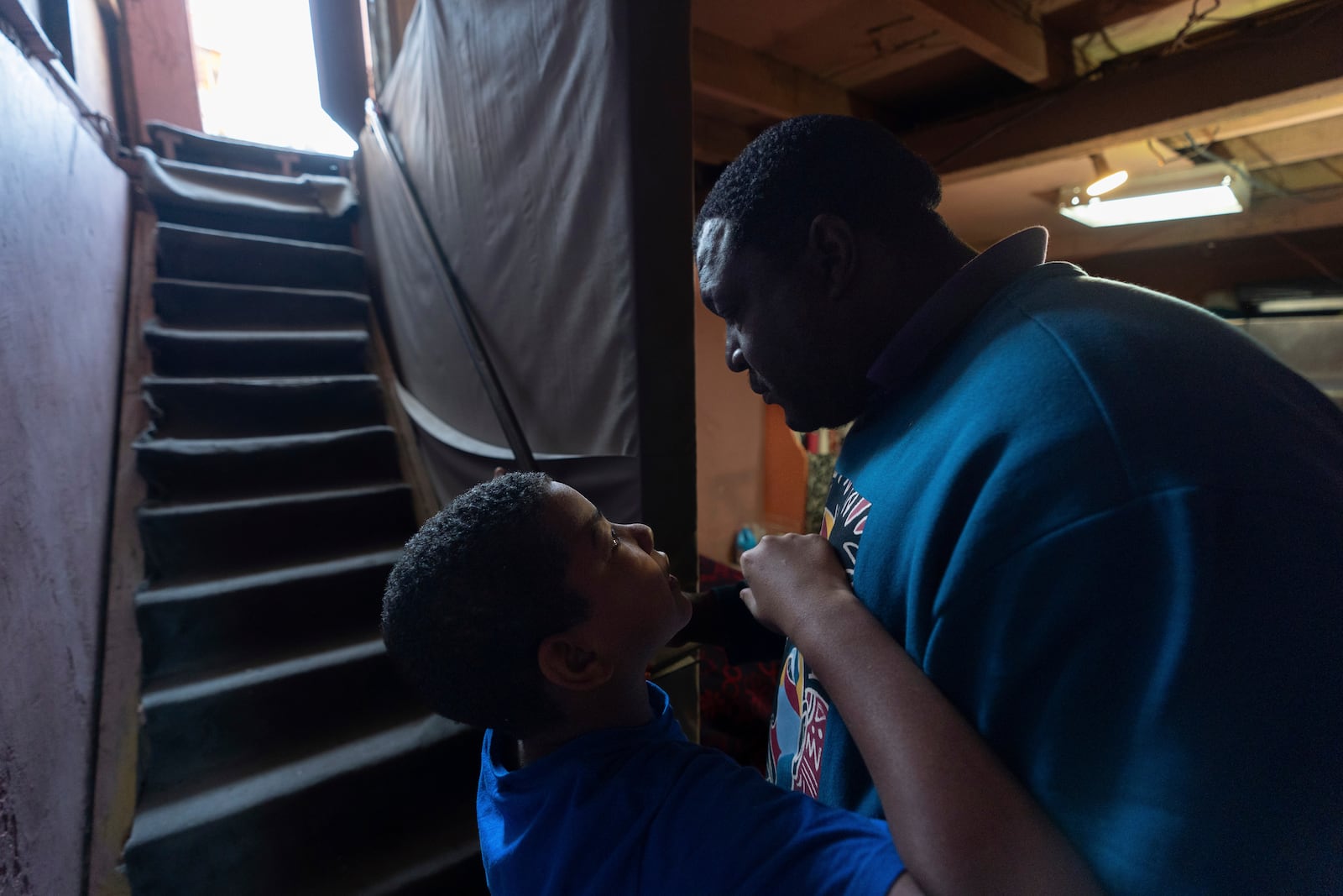 Migrant Dayron Garcia, of Cuba, embraces his son as they stay at Martha Rosales' house while waiting for an appointment to apply for asylum in the United States through the CBP One app Wednesday, May 22, 2024, in Tijuana, Mexico. (AP Photo/Gregory Bull)