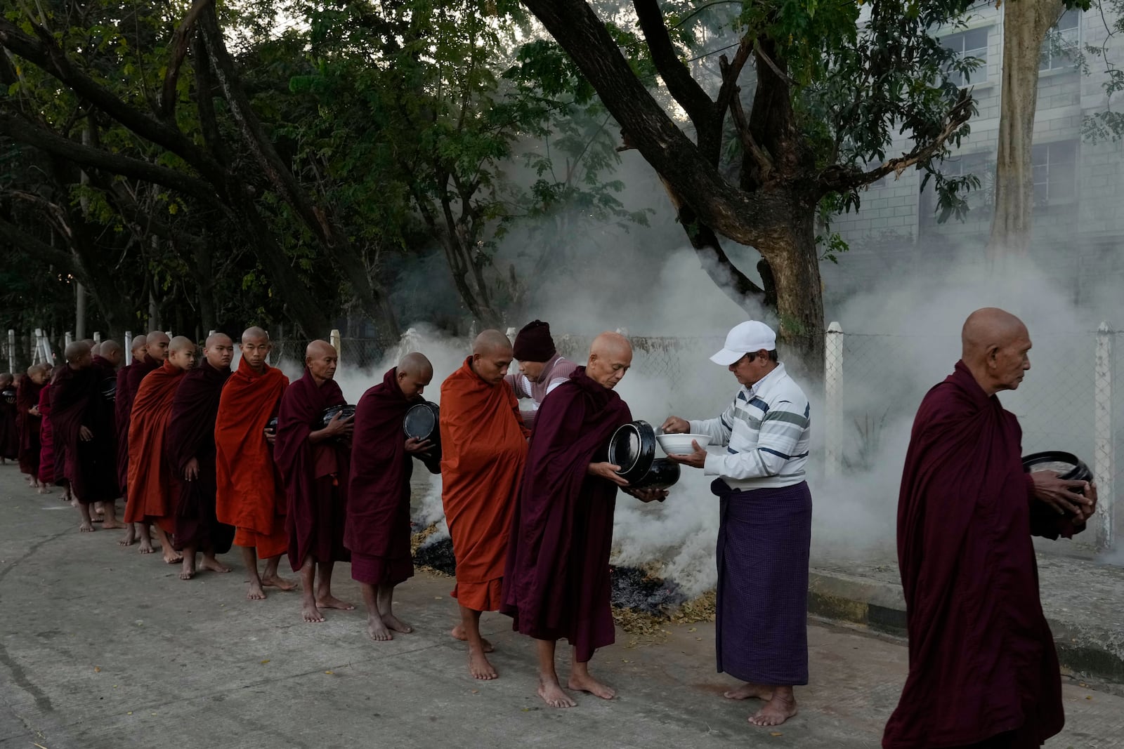 Buddhist monks line up to collect their morning alms from Buddhist devotees Saturday, Feb. 1, 2025, in Naypyitaw, Myanmar. (AP Photo/Aung Shine Oo)