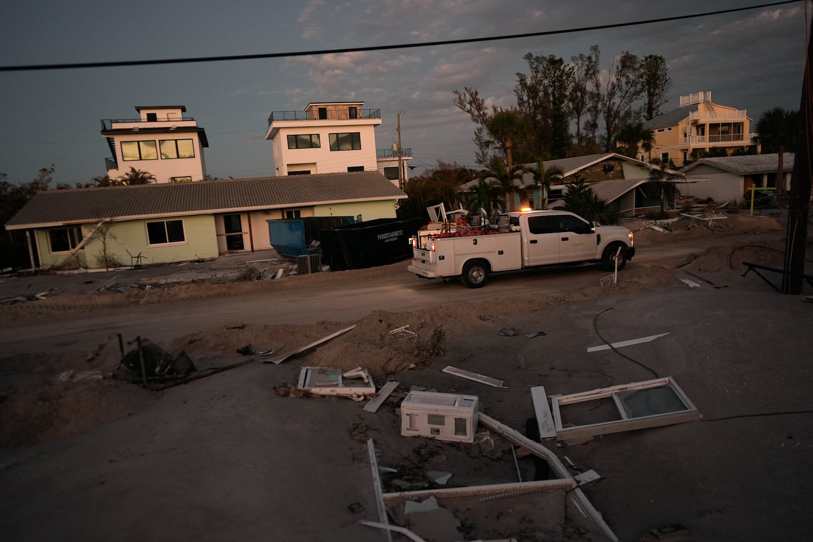 A county vehicle drives past damaged homes on Manasota Key, Fla., following the passage of Hurricane Milton, Saturday, Oct. 12, 2024. (AP Photo/Rebecca Blackwell)