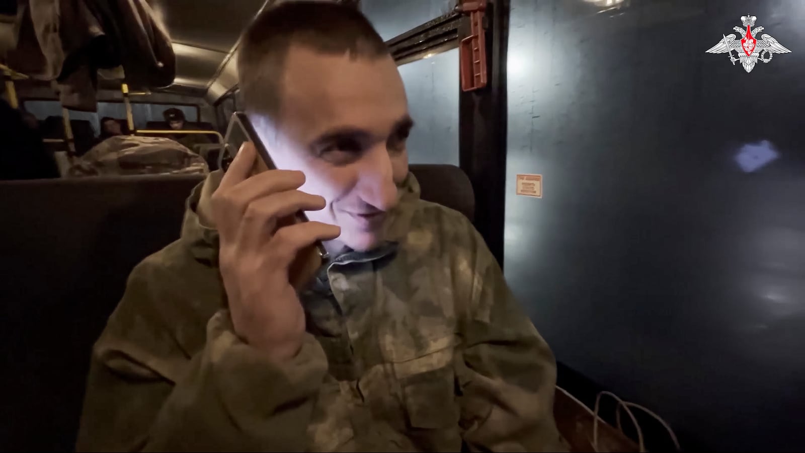 In this photo taken from video released by the Russian Defense Ministry Press Service on Monday, Dec. 30, 2024, a Russian soldier speaks on the phone with his relatives as he and others sit in a bus after being released in a prisoners swap between Russia and Ukraine, at an unspecified location in Belarus. (Russian Defense Ministry Press Service via AP)