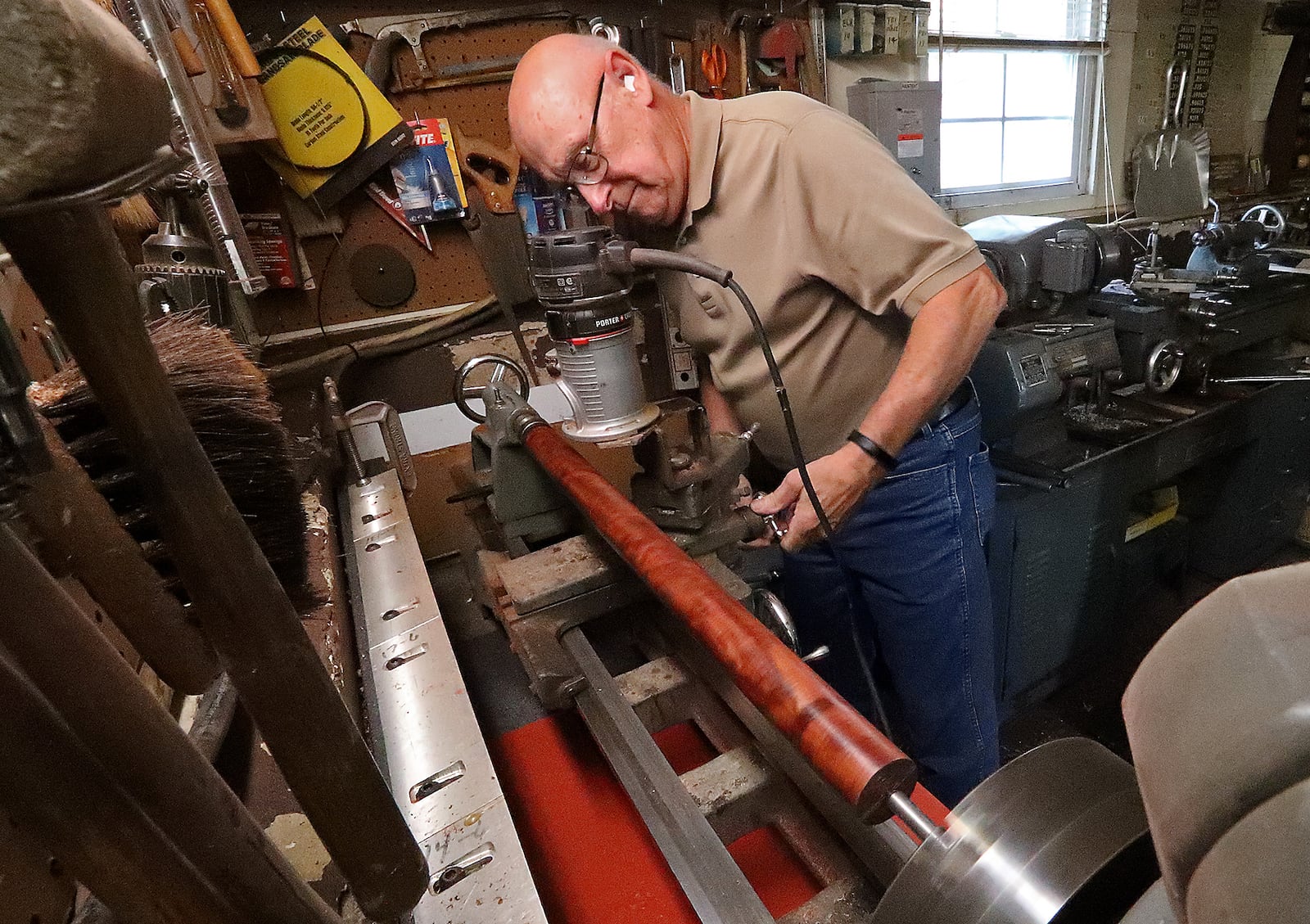 Jack Riley turns a piece of wood on a lathe as he works on a pool cue in his workshop. BILL LACKEY/STAFF