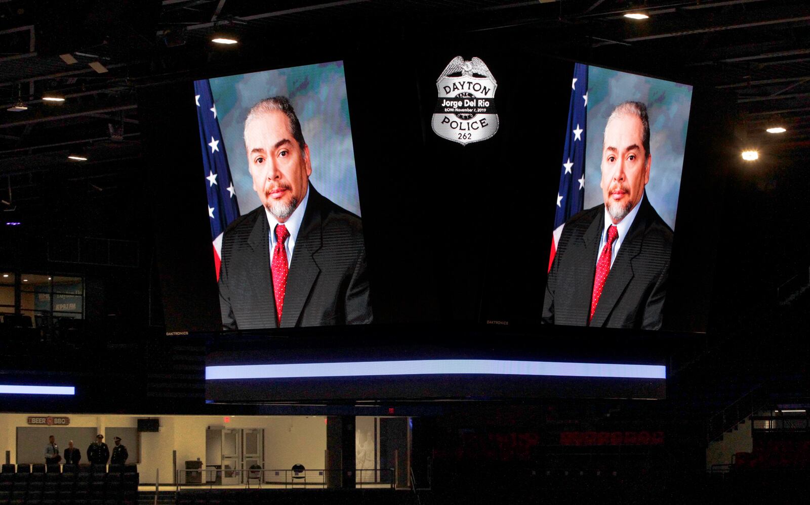 Photographs of Dayton Det. Jorge Del Rio are projected on the score board at the University of Dayton Arena during the public viewing Monday night. Del Rio was shot Nov. 4 while serving a search warrant on a suspected drug house. He will be honored with a procession Tuesday that will carry him through Dayton and the surrounding communities to a private service at Tobias Funeral Home.  LISA POWELL / STAFF