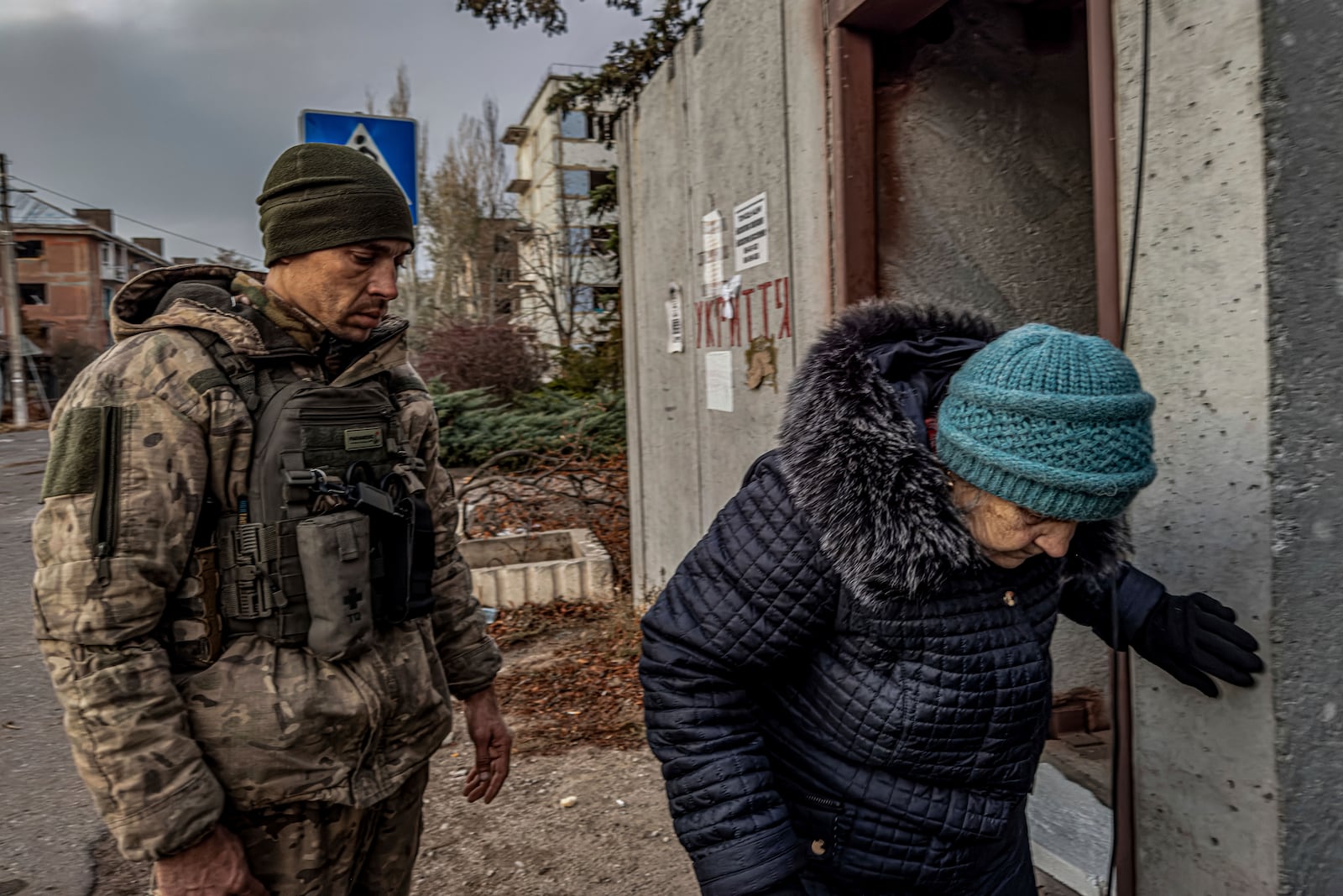 Pipa Vasyl, a policeman of the "White Angels" helps a local woman to sit down in an armoured van during en evacuation in Kurakhove, Donetsk region, Ukraine, on Nov. 7, 2024. (AP Photo/Anton Shtuka)