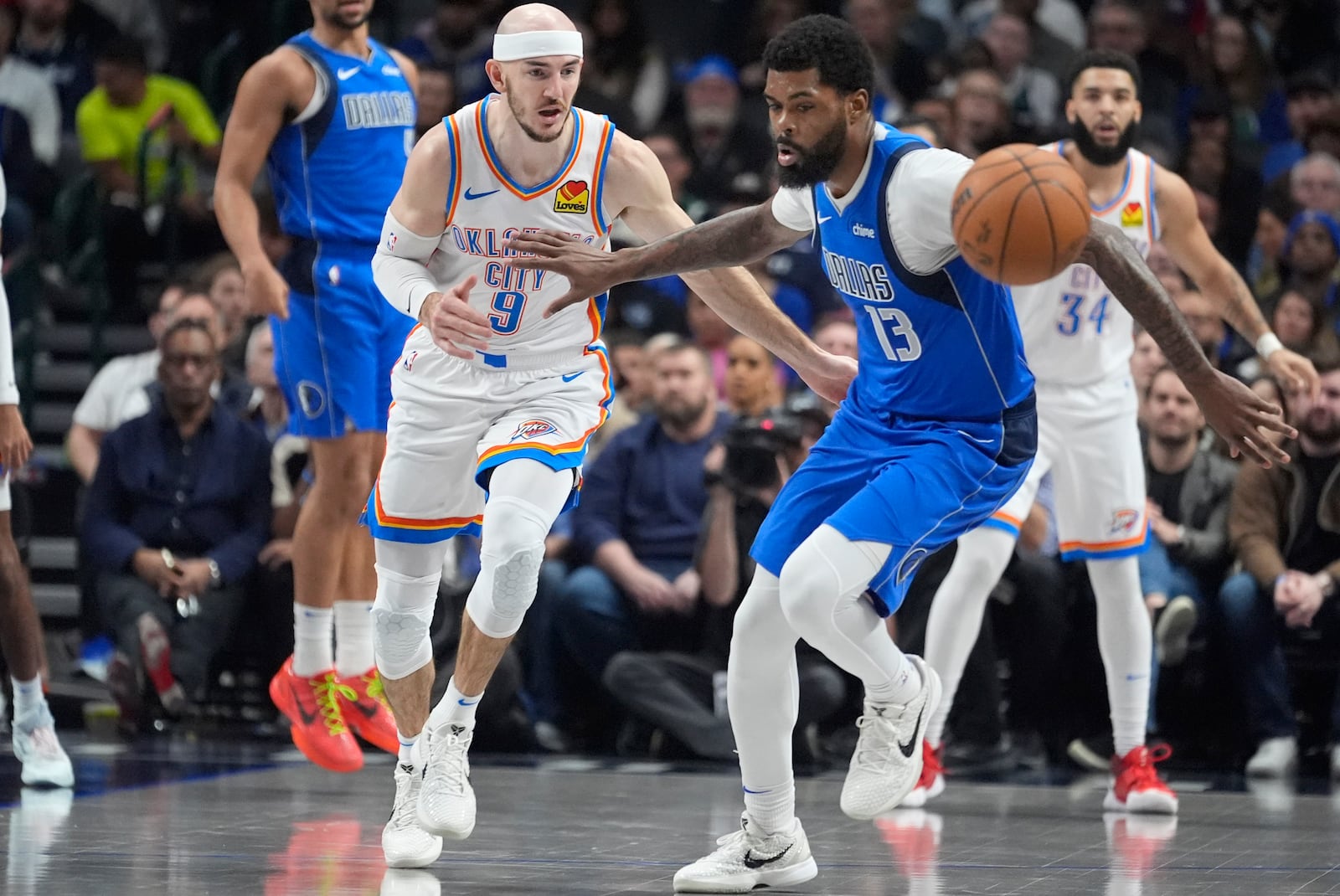 Dallas Mavericks forward Naji Marshall (13) and Oklahoma City Thunder guard Alex Caruso (9) chase the ball during the first half of an NBA basketball game Friday, Jan. 17, 2025, in Dallas. (AP Photo/LM Otero)