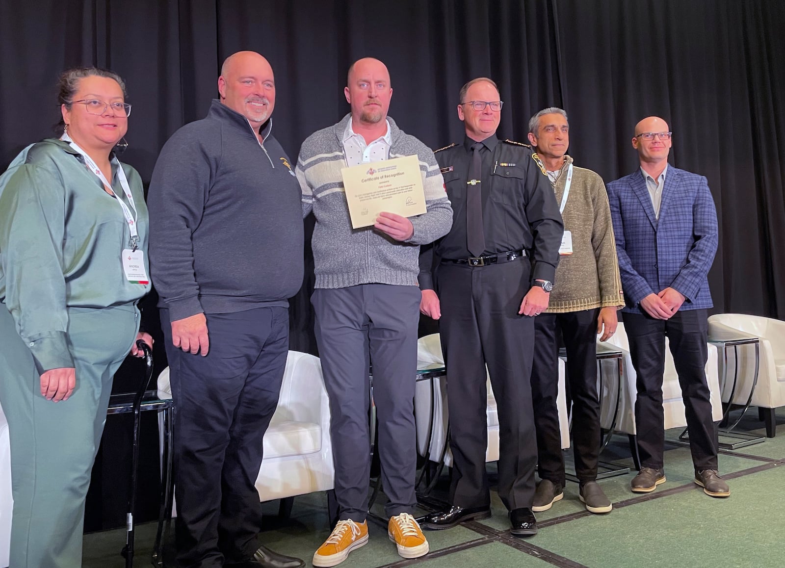 Pete Carlson, third from left, a passenger on the Delta flight that crashed in Toronto on Monday, holds a certificate of recognition for his actions in helping evacuate the plane and help fellow passengers, Wednesday, Feb. 19, 2025 in Toronto, Canada. (AP Photo/John Wawrow)