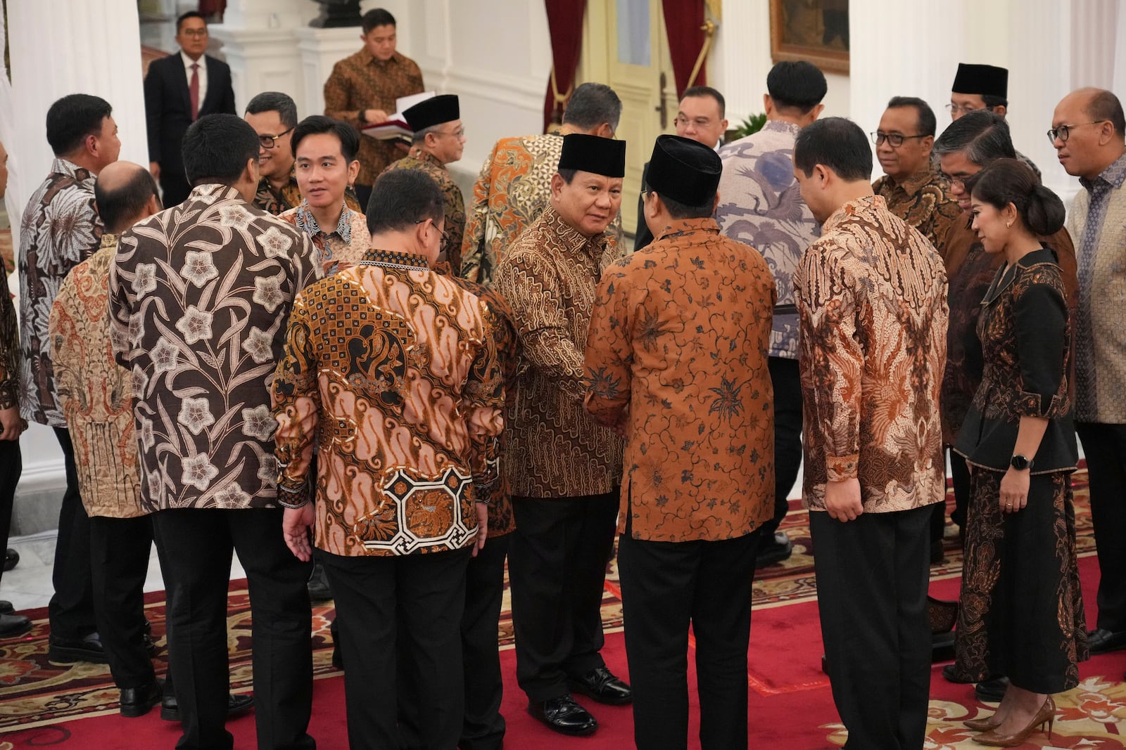 Indonesia's new President Prabowo Subianto, center, and Vice President Gibran Rakabuming Raka, left, shake hands with newly-appointed ministers after announcing their cabinet lineup at Merdeka Palace in Jakarta, Indonesia, Sunday, Oct. 20, 2024. (AP Photo/Achmad Ibrahim)