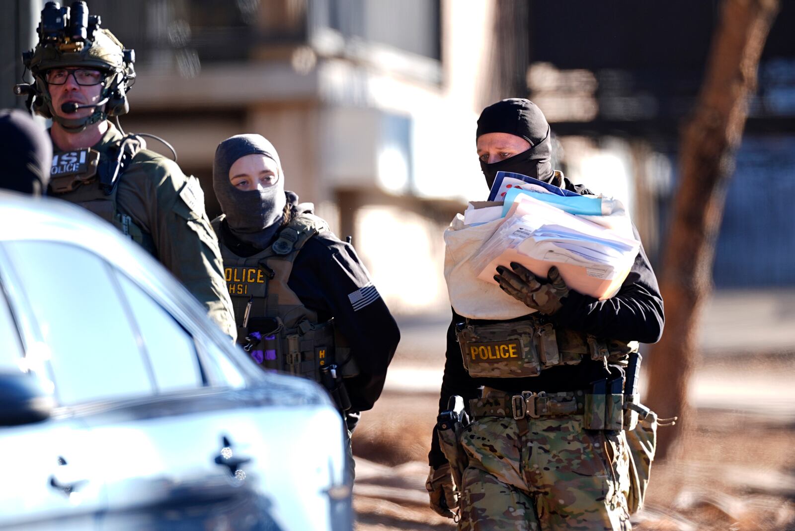 Law officials carry a stack of papers out of an apartment during a raid Wednesday, Feb. 5, 2025, in east Denver. (AP Photo/David Zalubowski)