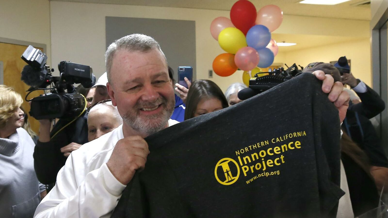 Ricky Davis holds up a Northern California Innocence Project T-shirt Thursday, Feb. 13, 2020, upon being released from prison after serving nearly 15 years for a murder he did not commit. A new suspect, Michael Green, right, has been charged with murder in the July 1985 stabbing death of newspaper columnist Jane Hylton, 54, in El Dorado Hills, Calif.