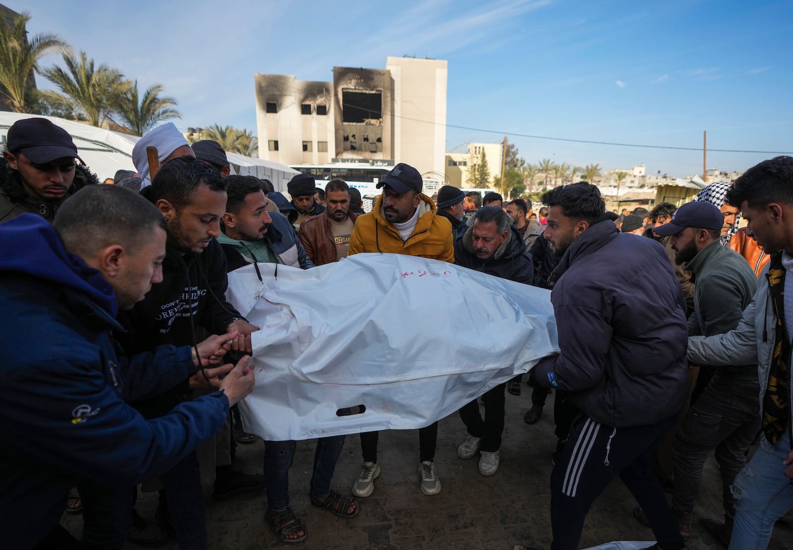 Palestinians carry white sacks containing the bodies of those killed in overnight Israeli airstrikes on the Khan Younis refugee camp, southern Gaza Strip, Saturday, Jan. 4, 2025. (AP Photo/Abdel Kareem Hana)