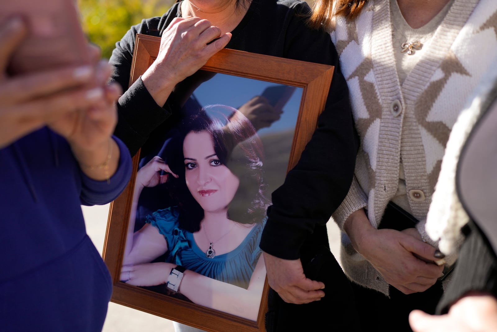 Soha Safadi holds a portrait of her sister, Sawsan, who lives inside the buffer zone near the "Alpha Line" that separates the Israeli-controlled Golan Heights from Syria, in the town of Majdal Shams, Wednesday, Dec. 18, 2024. (AP Photo/Matias Delacroix)