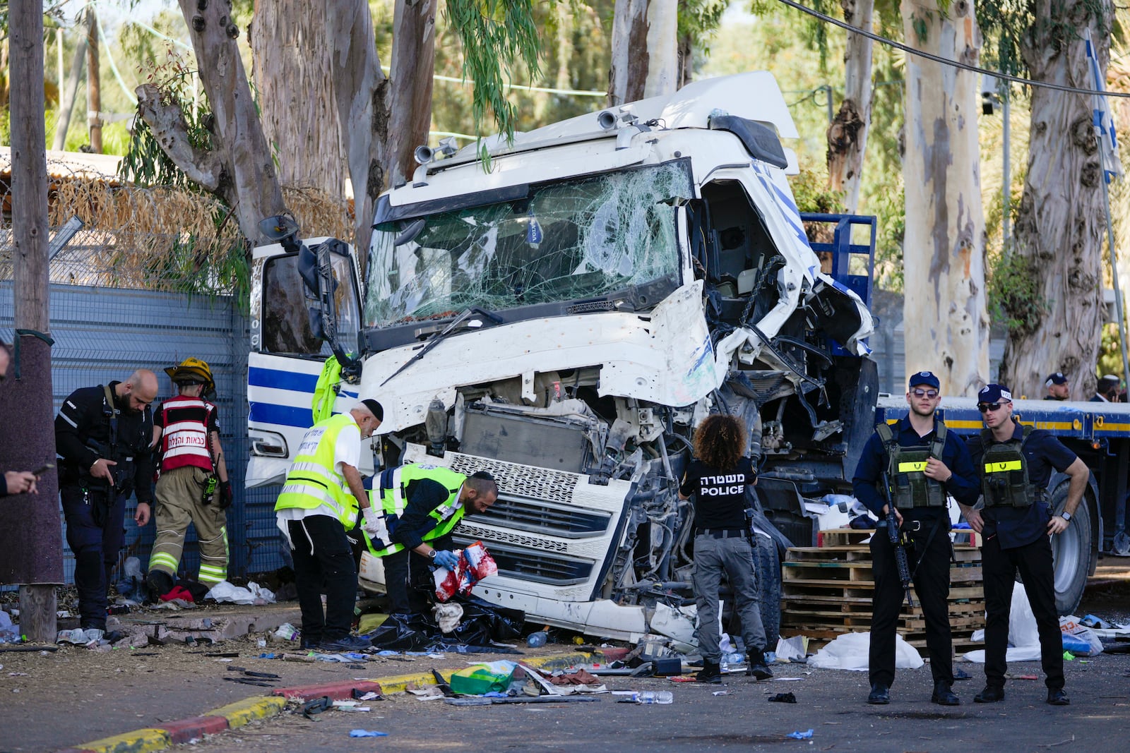 Israeli police and rescue services inspect the site where a truck driver rammed into a bus stop near the headquarters of Israel's Mossad spy agency, wounding dozens of people, according to Israel's Magen David Adom rescue service in Tel Aviv, Israel, Sunday, Oct. 27, 2024. (AP Photo/Ohad Zwigenberg)