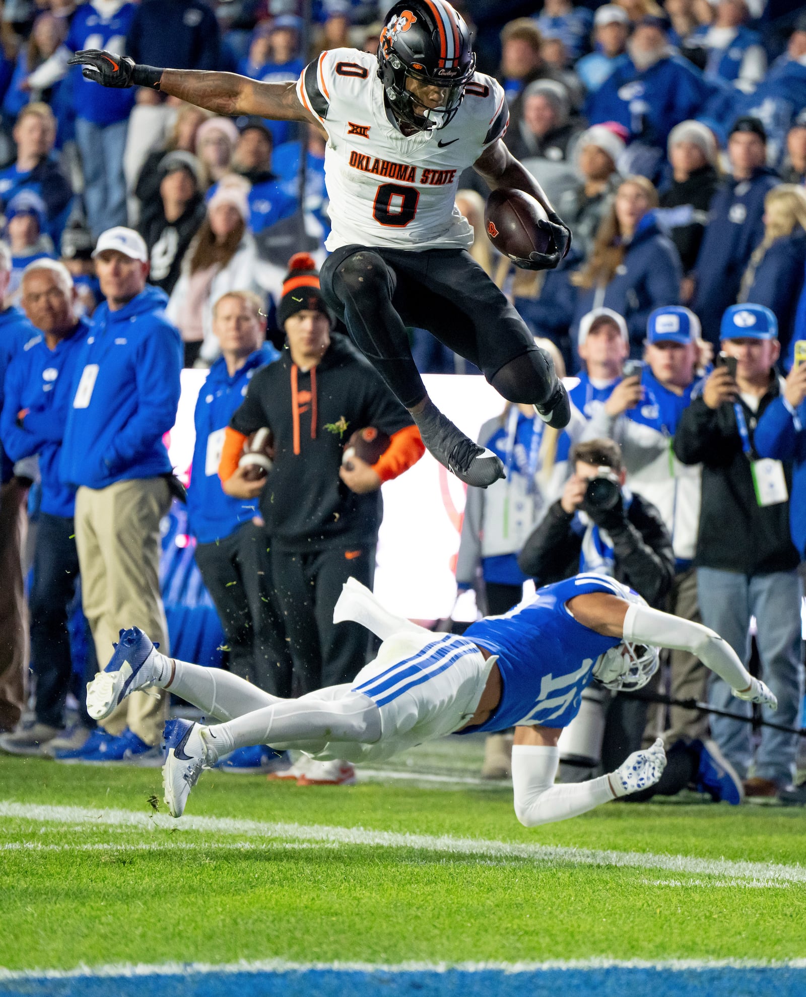 Oklahoma State running back Ollie Gordon II (0) hurdles over BYU safety Faletau Satuala (10) to score in the first half of an NCAA college football game, Friday, Oct. 18, 2024, in Provo, Utah. (AP Photo/Spenser Heaps)