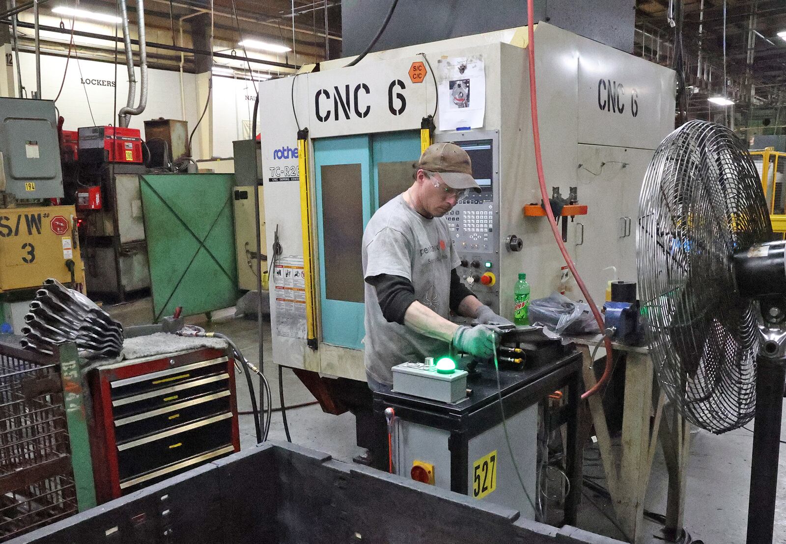 A worker at Pentaflex checks a part after taking it out of a CNC machine Wednesday. BILL LACKEY/STAFF