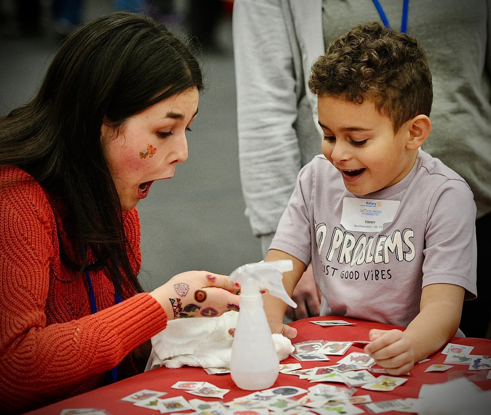 Grace Whitmore, left, reacts with Timmy Sisons, age 6, after putting a tattoo on his arm  Tuesday, December 12, 2023 at the Springfield Rotary 101st Children with Disabilities Christmas Party at the HWA center on the Wittenberg University campus. MARSHALL GORBY \STAFF