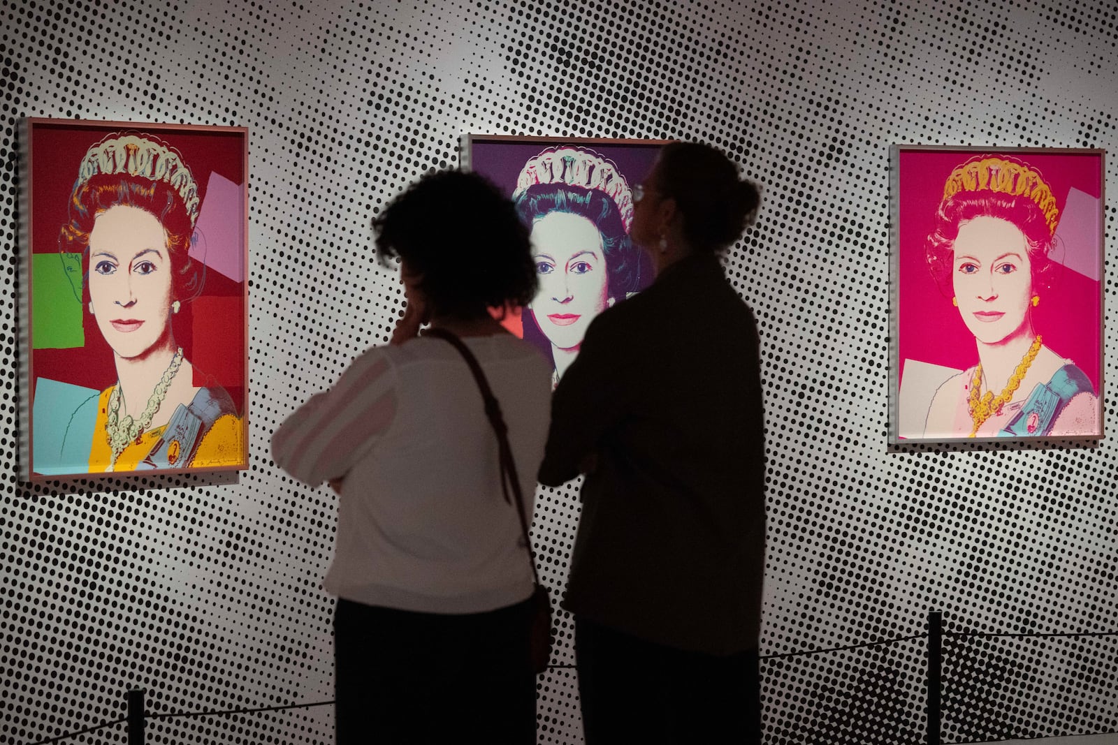 People look at screen print depicting Queen Elizabeth II, one in a series of sixteen prints of four queens titled Reigning Queens, 1985, by Andy Warhol at museum Paleis Het Loo in Apeldoorn, Netherlands, Wednesday, Oct. 9, 2024, similar to a Warhol work stolen from a gallery in Oisterwijk, Netherlands, early Friday, Nov. 1, 2024.(AP Photo/Peter Dejong)