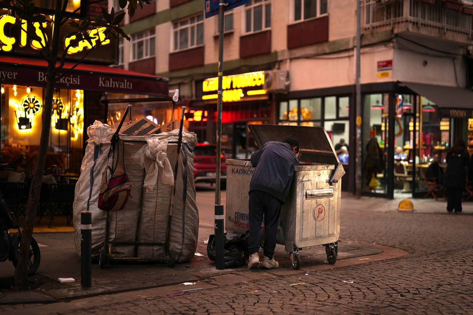 A boy scavenges for items from a trash can in the Kadikoy district in Istanbul, Turkey, Saturday, Dec. 7, 2024. (AP Photo/Francisco Seco)