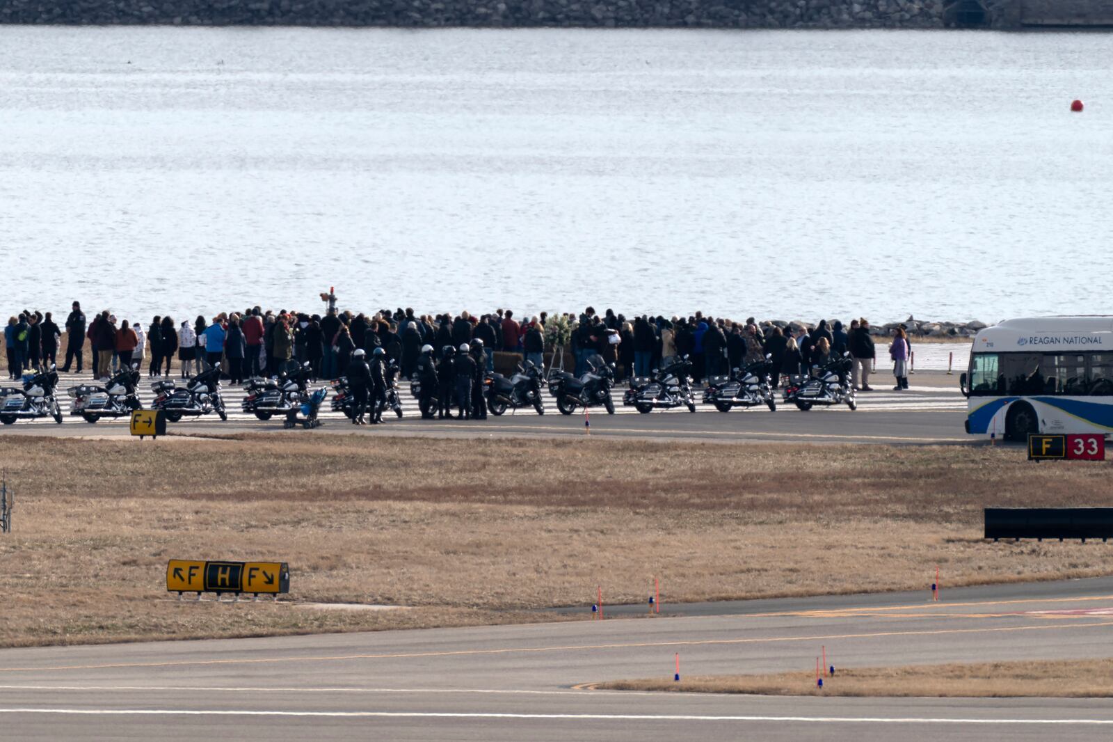 Families of the victims of a mid-air collision between an American Airlines jet and an Army helicopter stand near the wreckage site in the Potomac River at the end of the runway 33 from Ronald Reagan Washington National Airport, Sunday, Feb. 2, 2025, in Arlington, Va. (AP Photo/Jose Luis Magana)