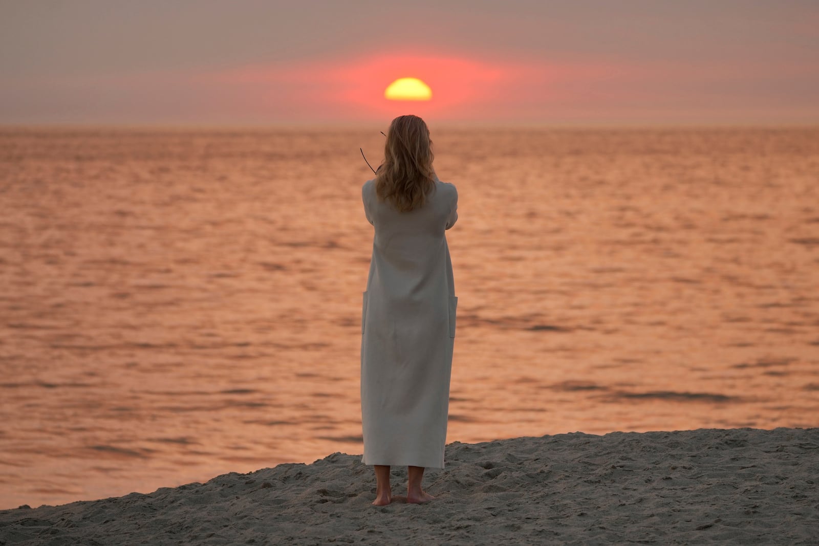 Screen writer and actress Sarah Newcome expresses her gratitude to God during sunset as a plume of smoke from the Franklin Fire rises over the ocean Tuesday, Dec. 10, 2024, in Malibu, Calif. (AP Photo/Damian Dovarganes)