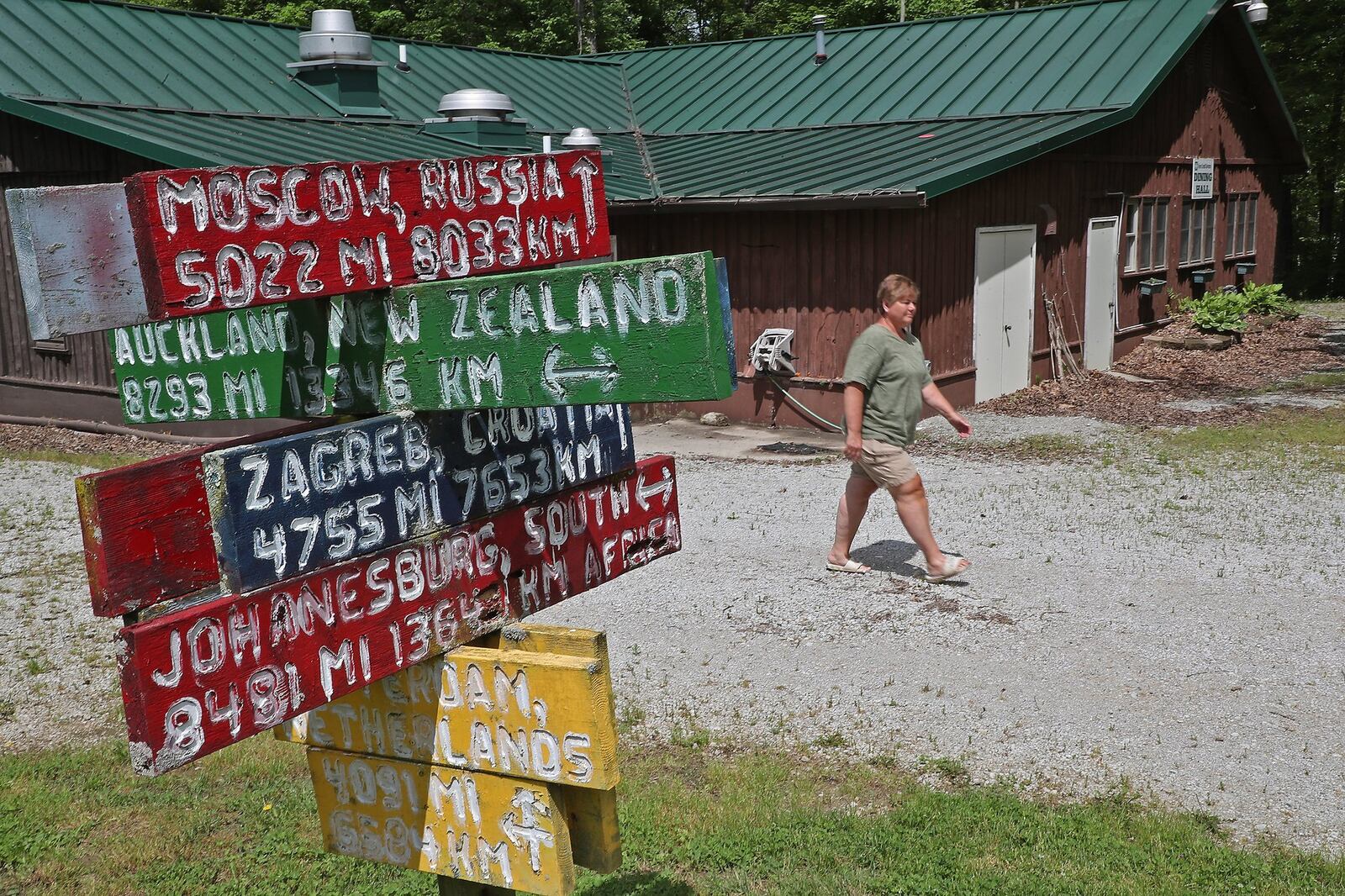 Terry Satchell walks past a sign at Camp Clifton dedicated to the international staff that have worked at the 4-H summer camp over the years. Terry and her husband, Glen, have been the camp directors for over 30 years and are having an online fund raiser to help pay for the upkeep of the camp since they can’t have any campers this year. BILL LACKEY/STAFF