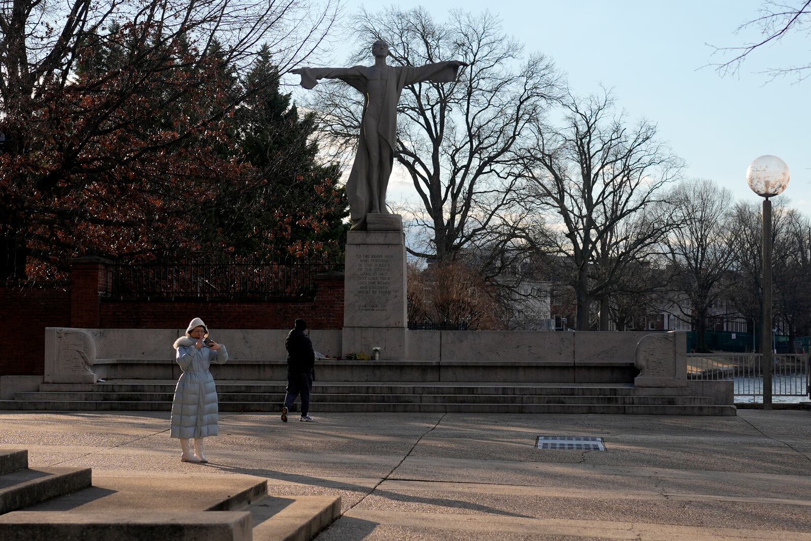 A visitor walks toward flowers and a letter left in memorial to the victims of a mid-air collision of an American Airlines jet and a Black Hawk helicopter near the Potomac river at the base of the Titanic Memorial, Saturday, Feb. 1, 2025, in Washington. (AP Photo/Carolyn Kaster)