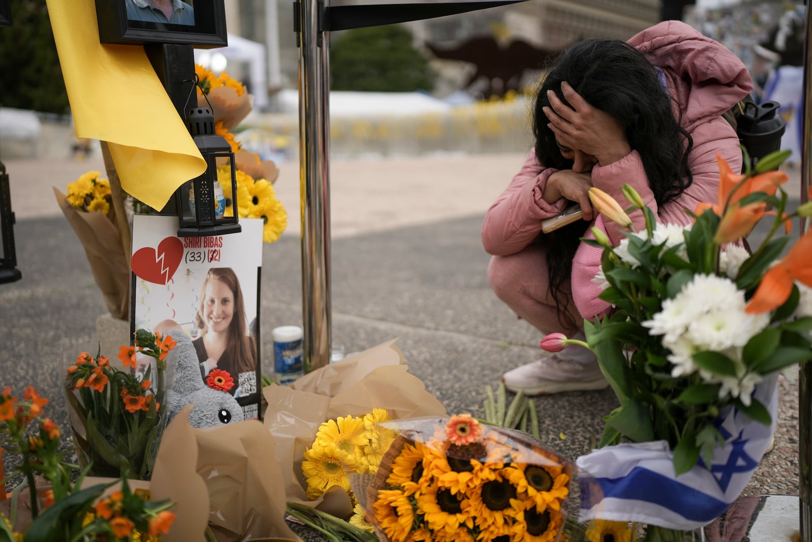 A woman mourns in a memorial for deceased hostages Shiri Bibas, her two children, Ariel and Kfir and Oded Lifshitz at 'Hostages Square, where Israelis are gathering while waiting for the release of six hostages in Gaza, in Tel Aviv, Israel, Saturday Feb. 22, 2025. (AP Photo/Oded Balilty)