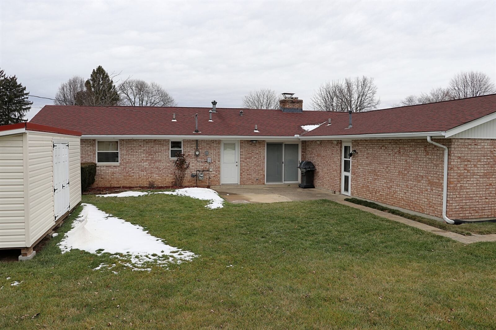 The property has a two-car, side-entry garage with concrete driveway and a deep backyard surrounded by a chain-link fence.