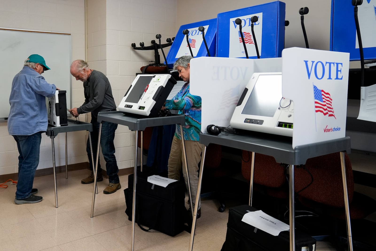 Poll workers set up ballot-marking machines at an early in-person voting site at Asheville-Buncombe Technical Community College, Wednesday, Oct. 16, 2024, in Marshall, N.C. (AP Photo/Stephanie Scarbrough)