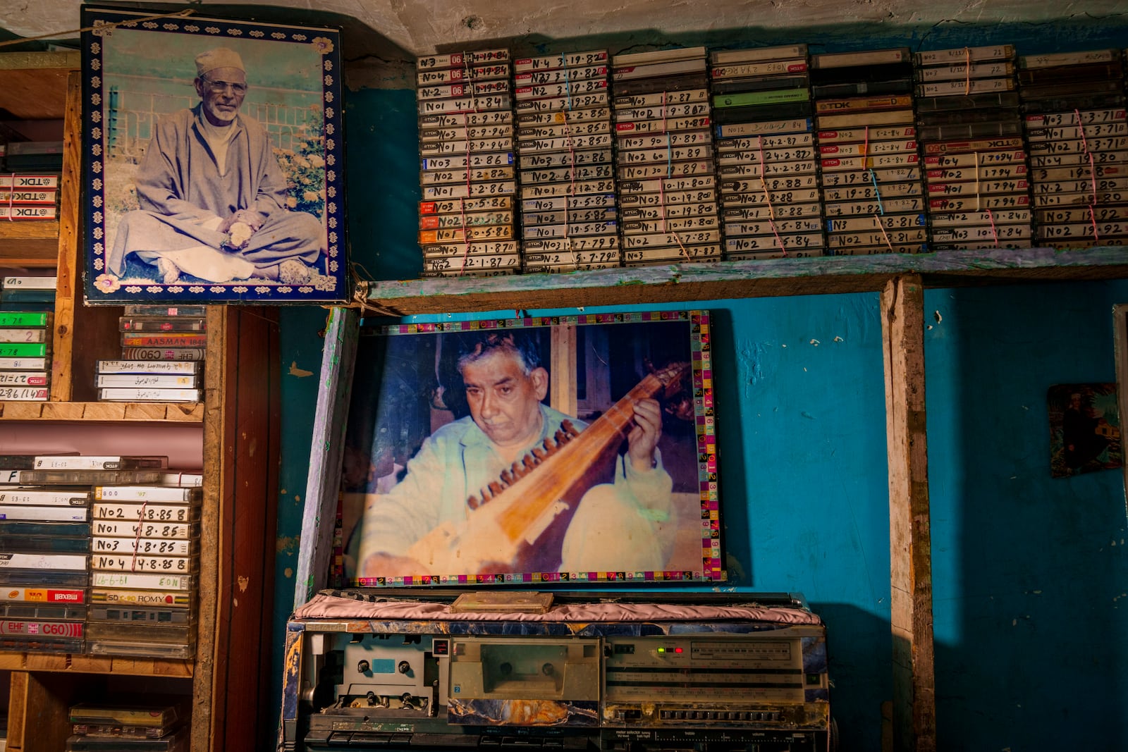 Photographs of Sufi saint Mohammad Rajab Shaksaz, left, and the late Sufi singer Ghulam Ahmad Sofi, center, along with a collection of his cassettes with his songs, are displayed inside a tailor shop owned by Farooq Ahmad Shaksaz in outskirts of Srinagar, Indian controlled Kashmir, Friday, Feb. 14, 2025. (AP Photo/Dar Yasin)