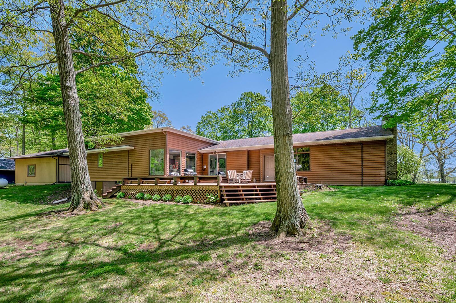 The rear of the home has a wood deck with double steps down and built-in benches and it sits on a wooded lot overlooking a golf course.