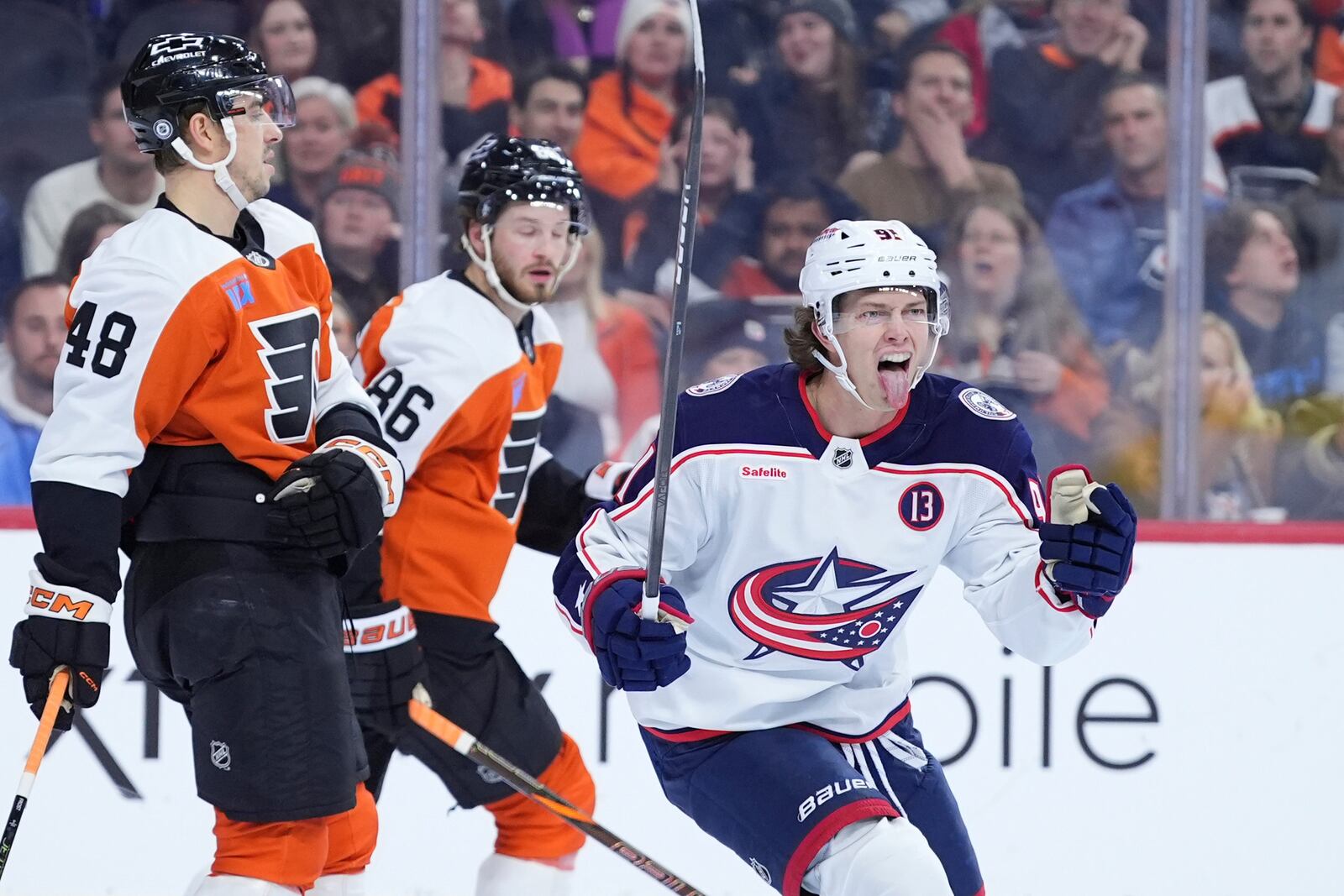 Columbus Blue Jackets' Kent Johnson, right, reacts after assisting on a goal by Mathieu Olivier during the first period of an NHL hockey game against the Philadelphia Flyers, Saturday, Dec. 21, 2024, in Philadelphia. (AP Photo/Matt Slocum)