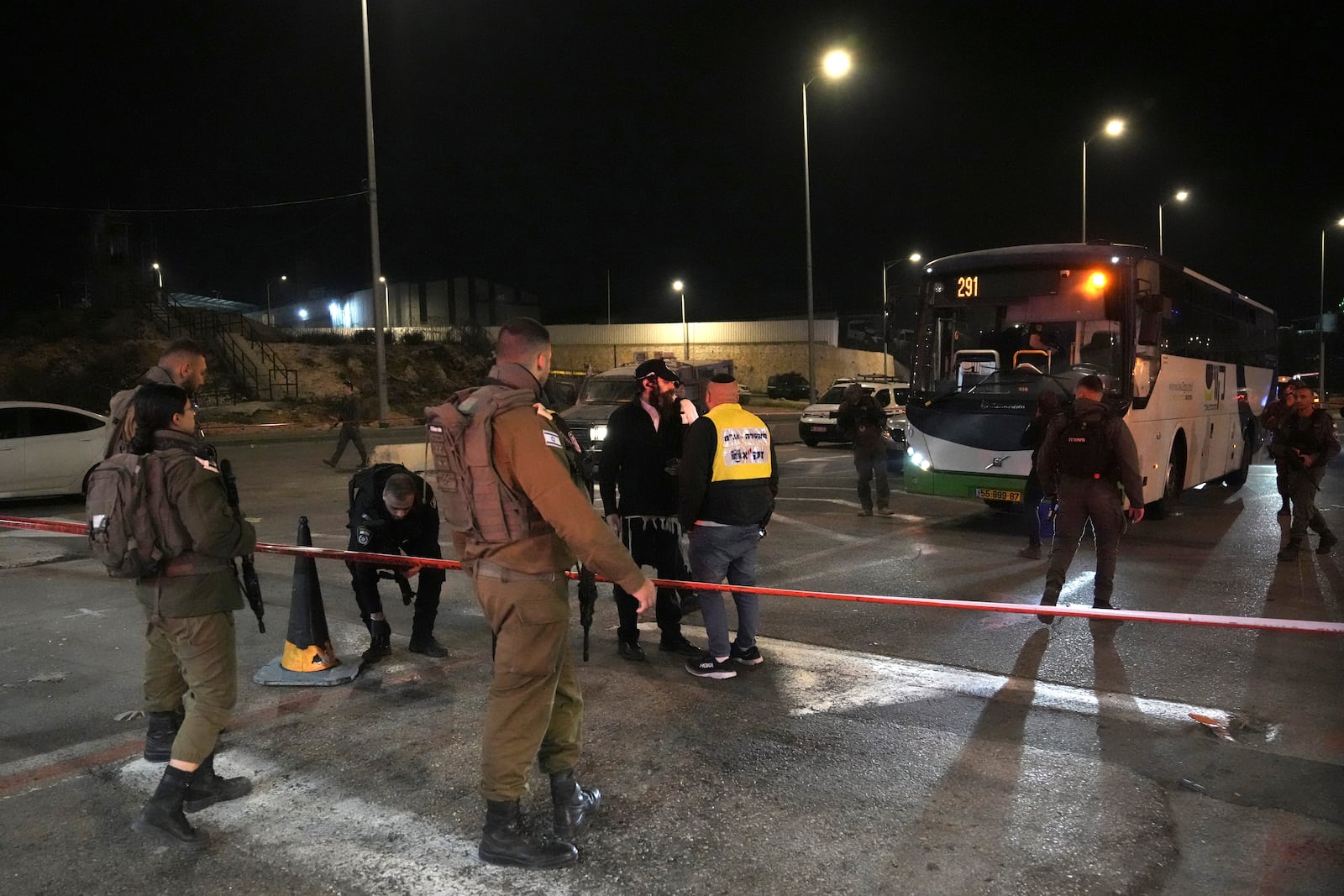 Israeli security forces work at the scene of a shooting attack on a bus near the West Bank town of Beit Jala, early Thursday, Dec. 12, 2024. (AP Photo/Mahmoud Illean)