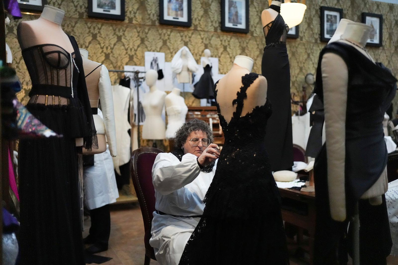 A seamstress works on a dress during the exhibition "From the Heart to the Hands: Dolce&Gabbana" at the Grand Palais, in Paris, Thursday, Jan. 9, 2025. (AP Photo/Thibault Camus)