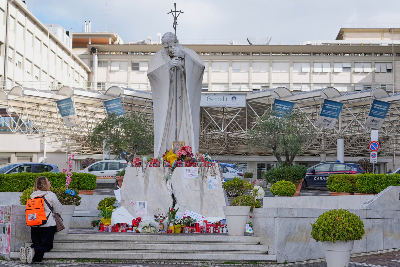 Samantha Brasini, of Italy, kneels in front of the statue of Pope John Paul II as she prays for Pope Francis outside the Agostino Gemelli polyclinic in Rome, Italy, Sunday, March 16, 2025. (AP Photo/Gregorio Borgia)