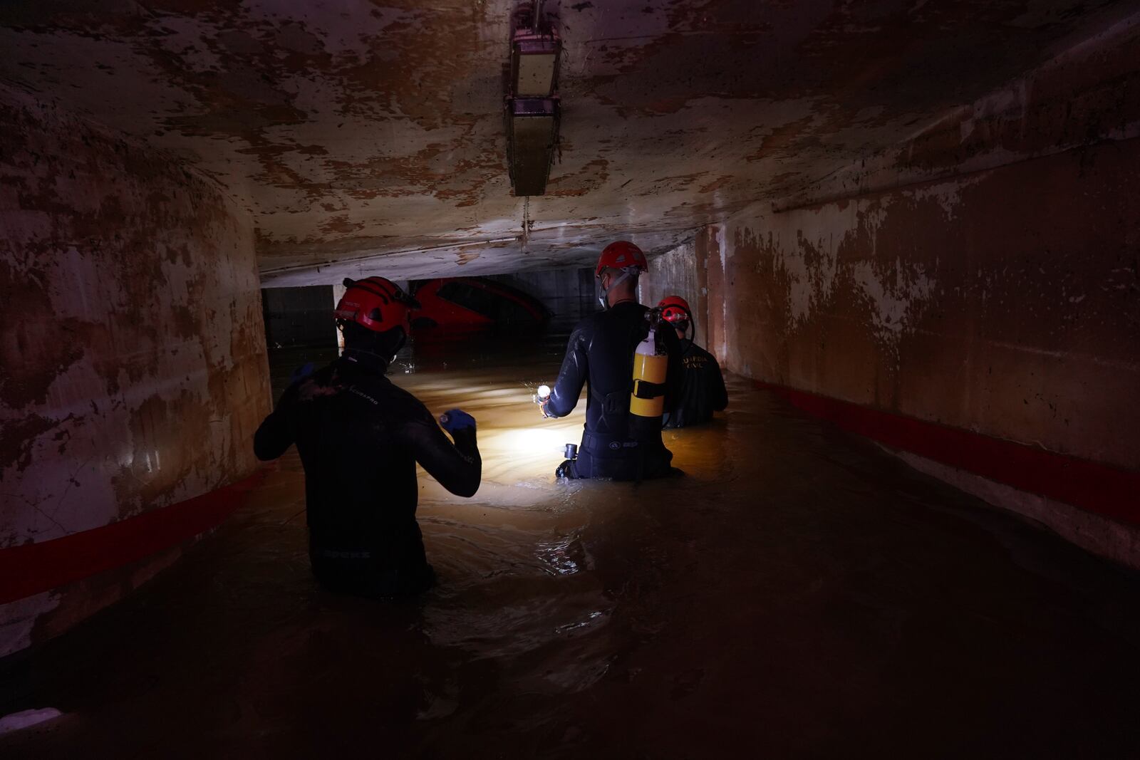 Civil Guards wade into an indoor car park to check cars for bodies after floods in Paiporta, near Valencia, Spain, Monday, Nov. 4, 2024. (AP Photo/Alberto Saiz)