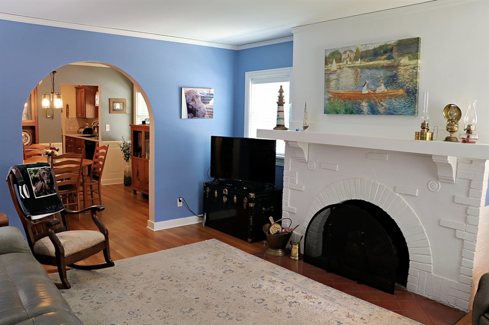 The front door opens directly into the living room with hardwood flooring that continues throughout the main level. The wood floors have been refinished to their beautiful honey oak color. A decorative fireplace has an arched opening and painted brick surround. There is a wood mantel and terra-cotta hearth.