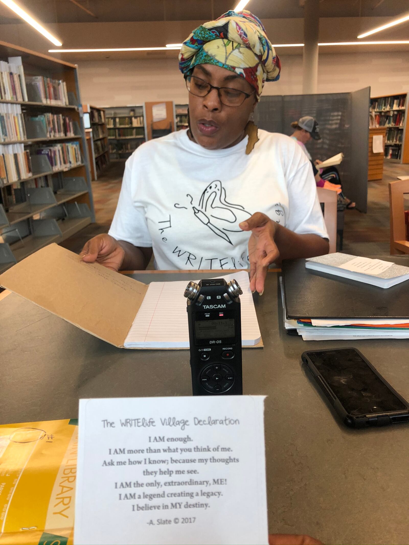 Dayton area resident shared stories of survival as part of the Dayton Strong Storytelling Sessions recorded at the Dayton Metro Library. Latesa Williamson, the Dayton poet and performer known as A Slate, of  The WRITElife Village is pictures. She holds a book of poems written by children following the tornadoes.