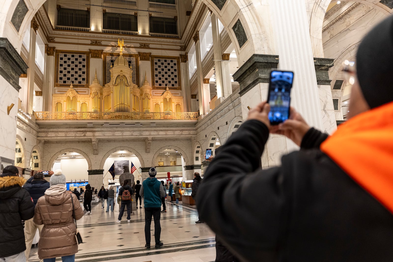 People gather inside Macy's to listen to one of the last moments of the Wanamaker Organ, Friday, Jan. 10, 2025, in Philadelphia. (Tyger Williams/The Philadelphia Inquirer via AP)