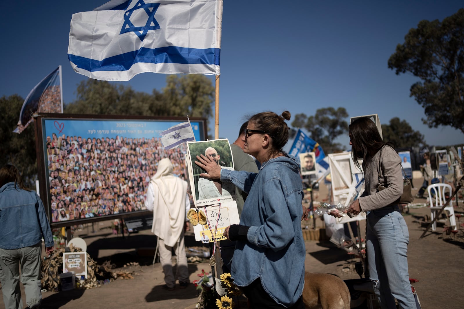 A woman pauses to touch the memorial marker of her loved one, Bar Lior Nakmuli, at the site of the Nova music festival, where hundreds of revelers were killed or kidnapped by Hamas, on the Jewish holiday of Simchat Torah, marking one year in the Hebrew calendar since the attack, near Kibbutz Re'im, southern Israel near the Gaza Strip, Thursday, Oct. 24, 2024. (AP Photo/Maya Alleruzzo)