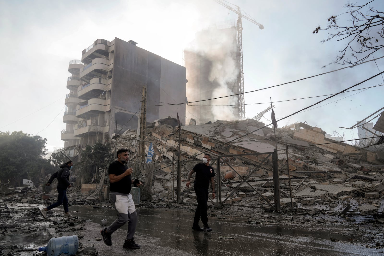 Residents run as smoke rises from a building that collapsed after it was hit by an Israeli airstrike in Chiyah, south of Beirut, Lebanon, Sunday, Nov. 17, 2024. (AP Photo/Bilal Hussein)