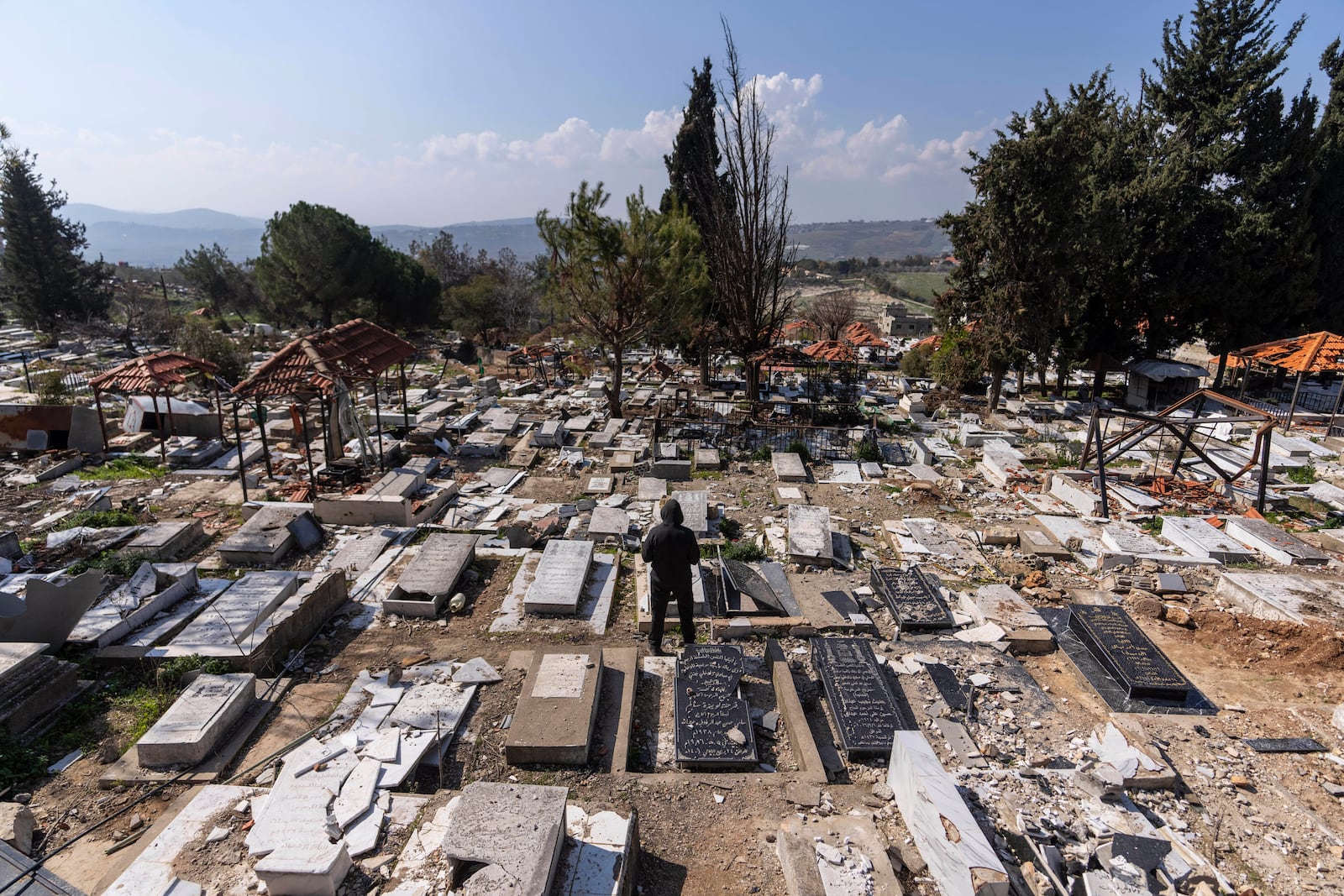 A man prays at the damaged cemetery, caused by the Israeli air and ground offensive, in Khiam, southern Lebanon, Monday, Feb. 17, 2025. (AP Photo/Hassan Ammar)