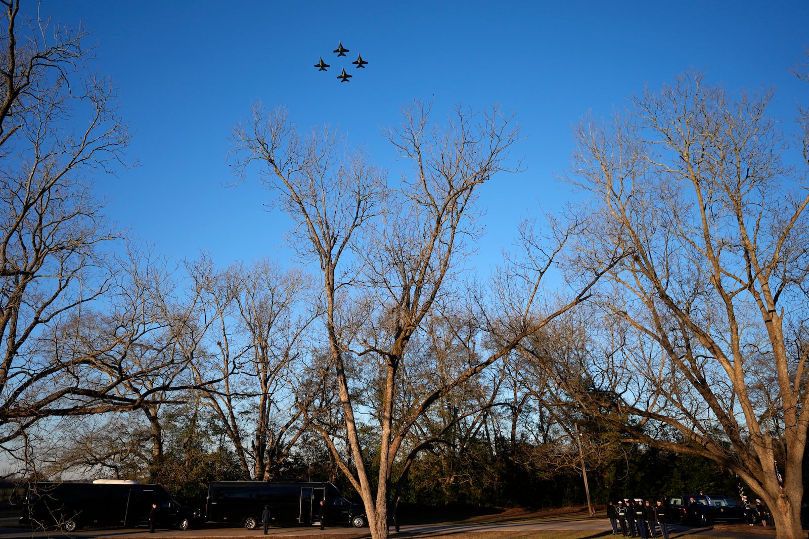 U.S. Navy F/A-18 Super Hornets perform a fly-over as as the casket of former President Jimmy Carter, bottom right, arrives at Maranatha Baptist Church for a funeral service, Thursday, Jan. 9, 2025, in Plains, Ga. (AP Photo/Mike Stewart)