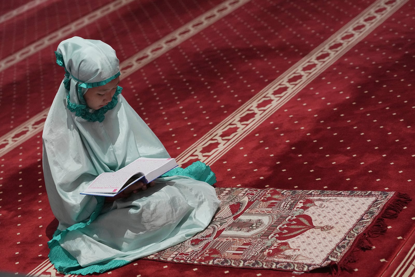 A Muslim woman reads Quran during the first day of the holy fasting month of Ramadan at Istiqlal mosque in Jakarta, Indonesia, Saturday, March 1, 2025. (AP Photo/Achmad Ibrahim)