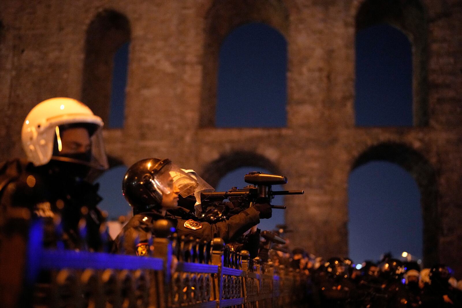 A policeman uses an anti riot rifle to disperse people during a protest against the arrest of Istanbul's Mayor Ekrem Imamoglu in Istanbul, Turkey, Friday, March 21, 2025. (AP Photo/Emrah Gurel)