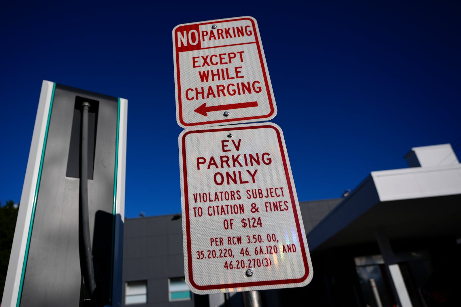 Parking signs are seen at an Electrify America charging station, Wednesday, Oct. 9, 2024, in Seattle. (AP Photo/Lindsey Wasson)