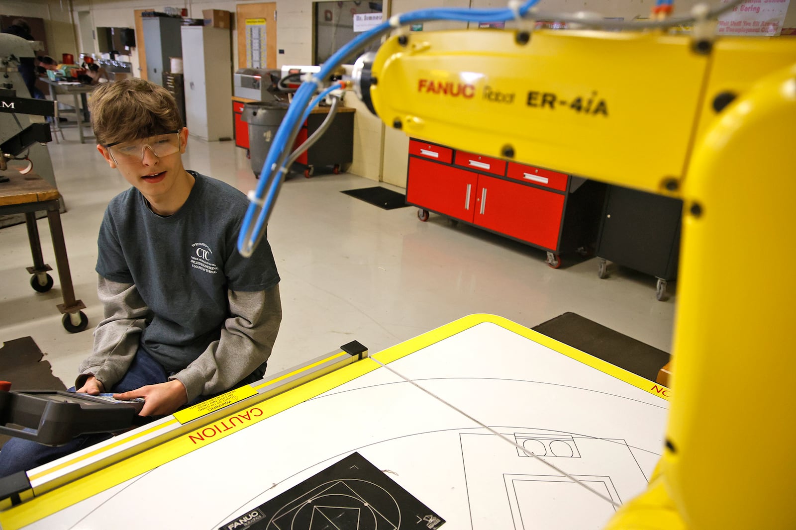 Owen Deer sits at the controls of a robotic arm Tuesday, Feb. 13, 2024 in a manufacturing lab. The program is one of the more popular at CTC and some students are turned away because of a lack of classroom space. The Applied Engineering & Manufacturing program teaches the basics of engineering, manufacturing, robotics, and welding and fabrication. Many students in this program work part-time at local manufacturing businesses through CTC’s work-placement program. BILL LACKEY/STAFF